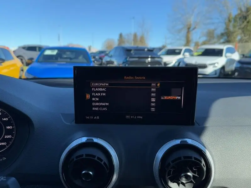 Vue intérieure du tableau de bord d'un Audi Q2 30 TDI S line 2024, écran multimédia affichant les radios FM.