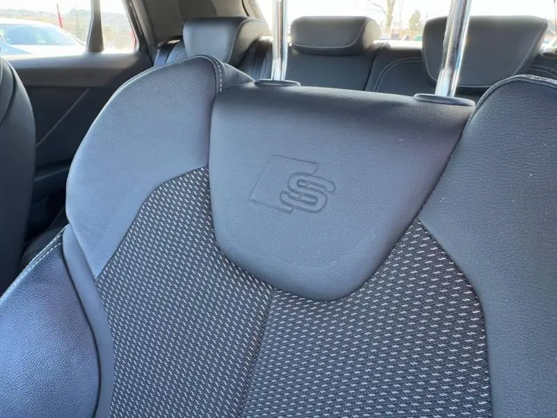 Gros plan sur le siège avant sport noir de l'Audi Q2 30 TDI S line 2024 avec logo S embossé sur l'appuie-tête.