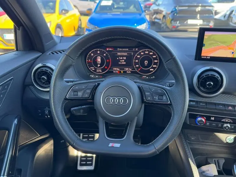 Vue intérieure centrée sur le volant sport Audi Q2 30 TDI 2024 avec tableau de bord numérique et écran GPS.