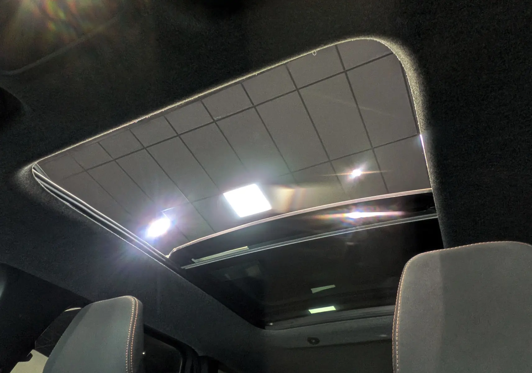 Toit panoramique ouvert vu de l'intérieur du Dacia Bigster 2026, avec ciel et éclairage intérieur visibles.