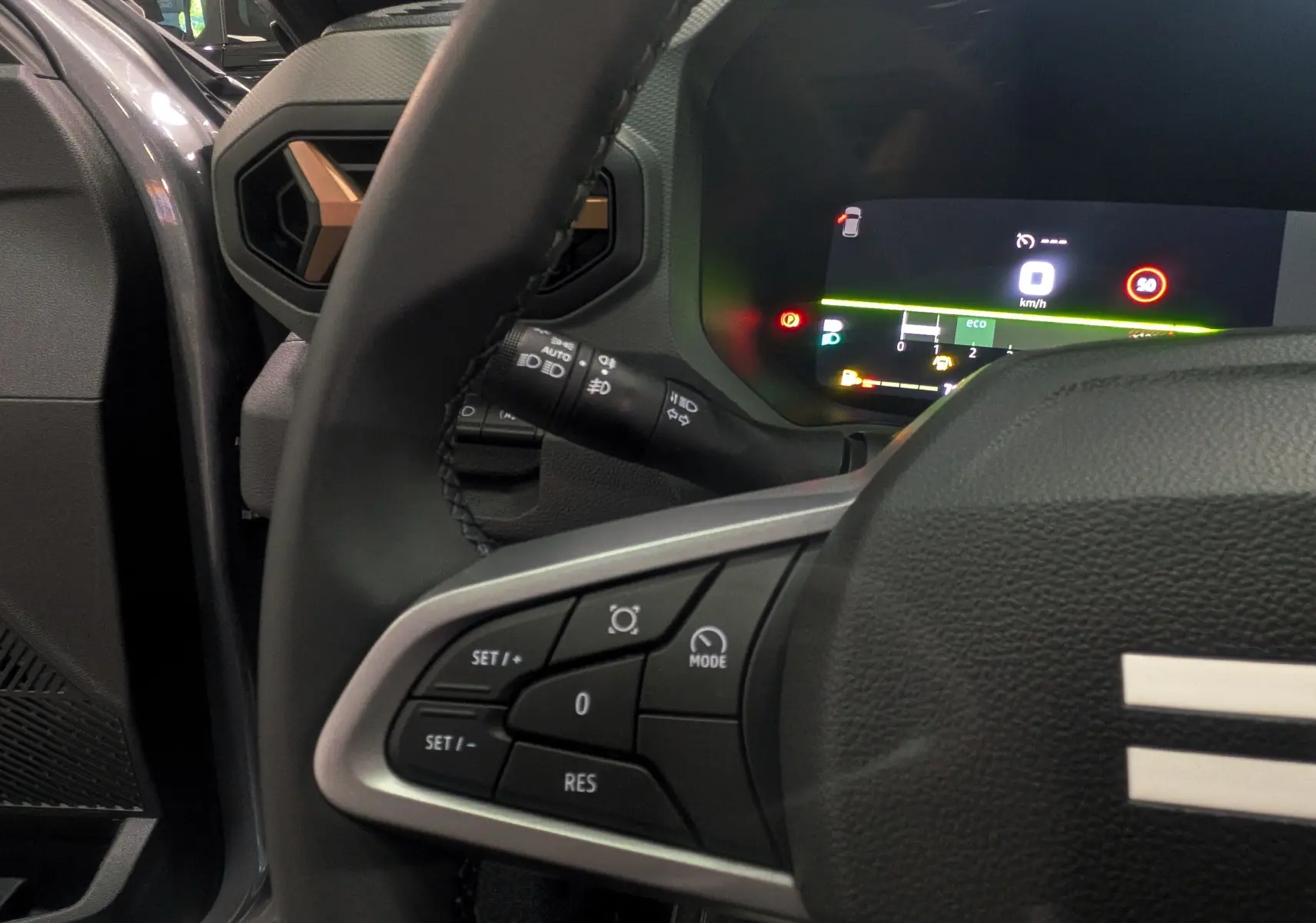 Vue rapprochée du volant et du tableau de bord numérique du Dacia Bigster gris schiste, avec commandes au volant visibles.