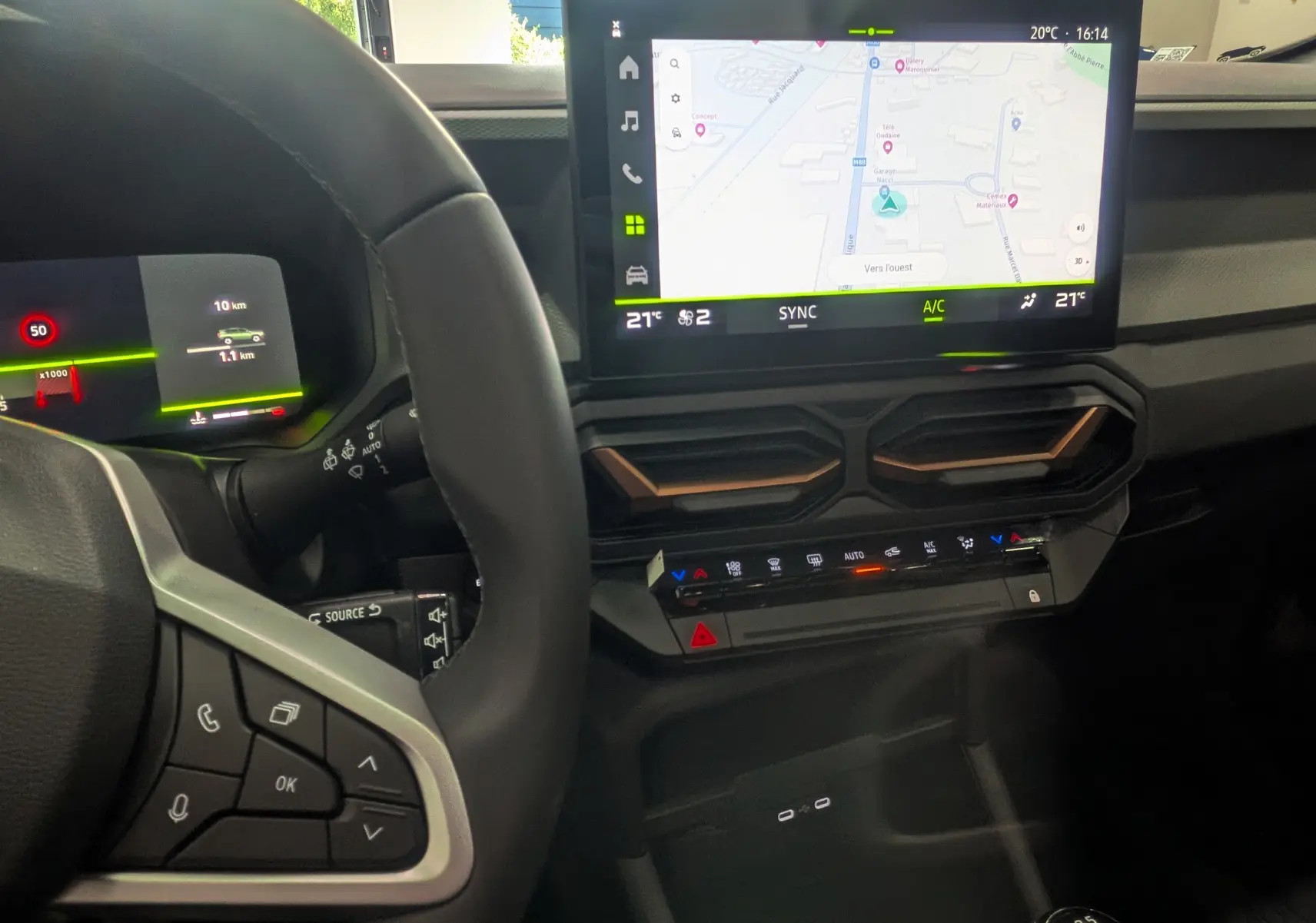 Vue intérieure du tableau de bord du Dacia Bigster gris, avec écran tactile central affichant la navigation et commandes climatisation.