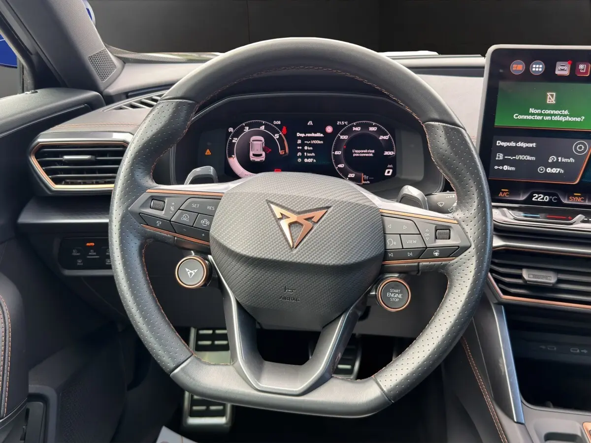 Vue centrée sur le volant cuir perforé noir avec logo CUPRA, tableau de bord numérique et écran tactile central.