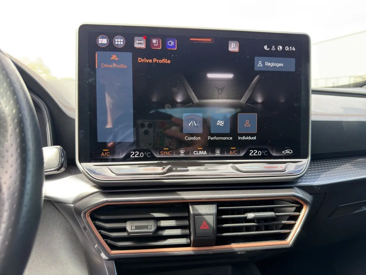 Vue intérieure du tableau de bord du CUPRA Formentor avec écran tactile central affichant les modes de conduite, détails en noir et cuivre.