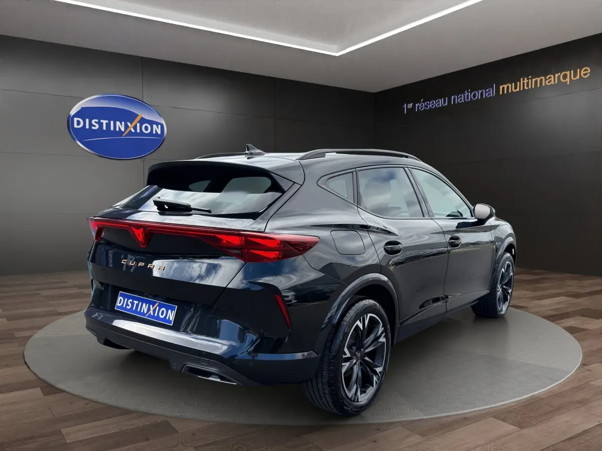 Vue 3/4 arrière droite d'une CUPRA Formentor noire avec feux arrière LED distinctifs dans un showroom.