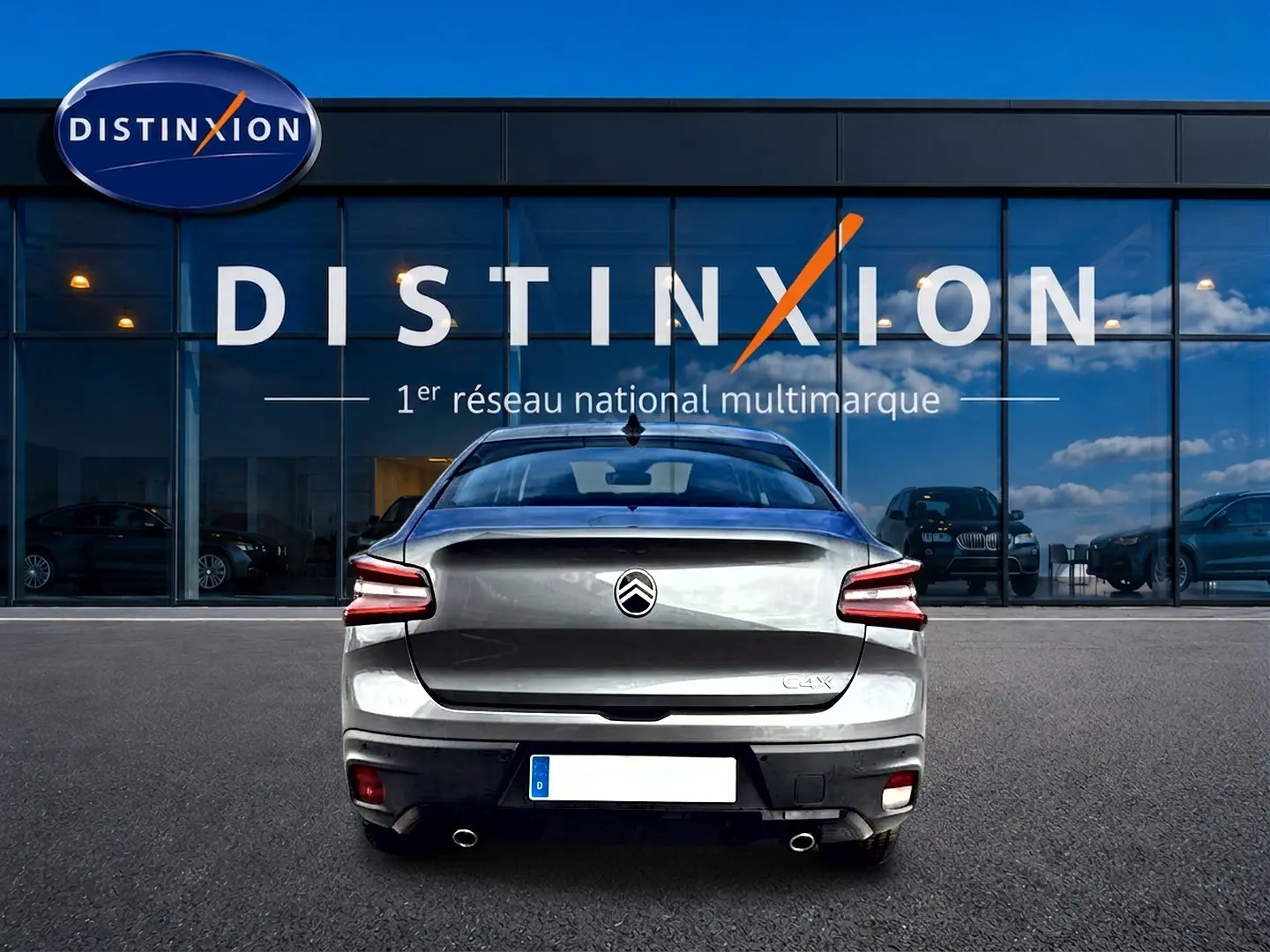 Vue arrière d'une Citroën C4 X gris mercure stationnée devant une vitrine avec logo Distinxion.