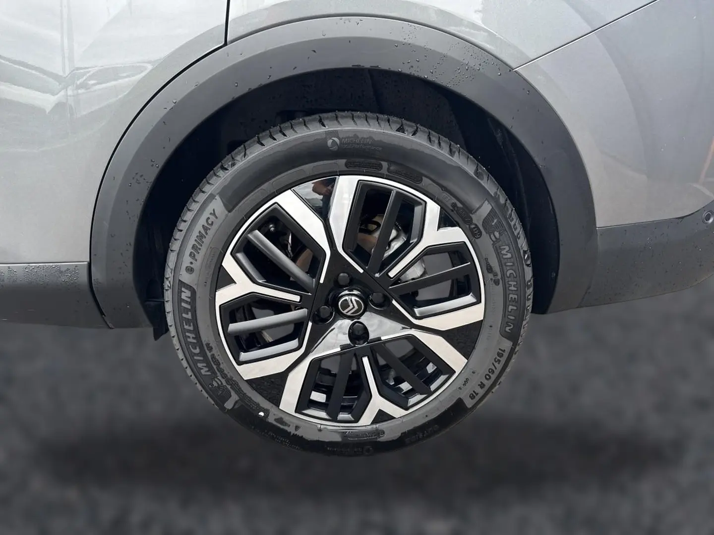 Gros plan sur la roue arrière droite gris mercure d'une Citroën C4 X 1.2 hybride avec jante alu bicolore distinctive.