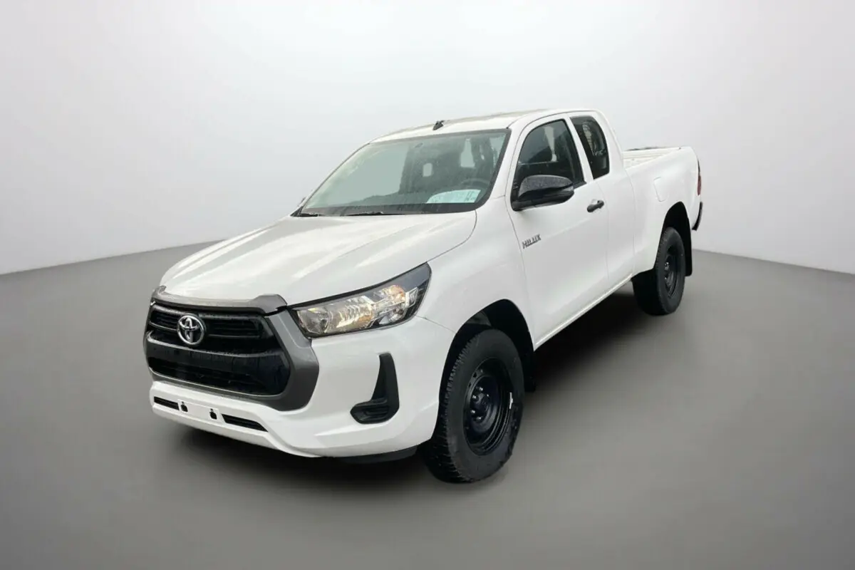 Toyota Hilux 4x4 blanc pur en 3/4 avant droit, avec calandre noire et jantes acier noires visibles.