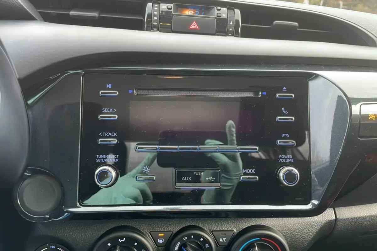 Vue rapprochée du tableau de bord noir du Toyota Hilux 4x4 2024 montrant l’écran multimédia et les commandes climatisation.