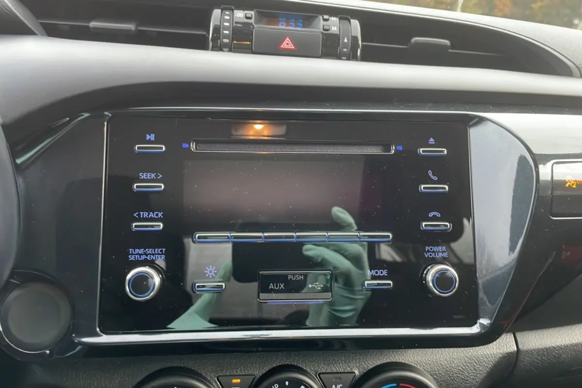 Vue rapprochée du tableau de bord noir du Toyota Hilux 2024, mettant en valeur l'écran tactile et les commandes audio.