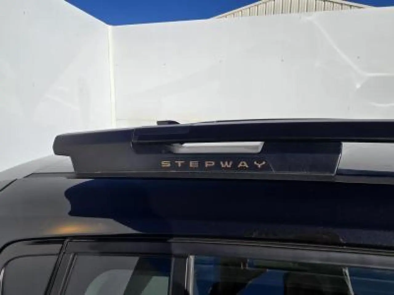 Gros plan sur la barre de toit arrière noire nacrée avec inscription Stepway brun cuirvré sur Dacia Sandero III Stepway.