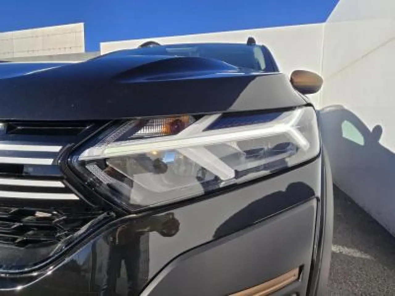 Gros plan sur le phare avant droit d'une Dacia Sandero Stepway 2025 noir nacré avec calandre chromée.