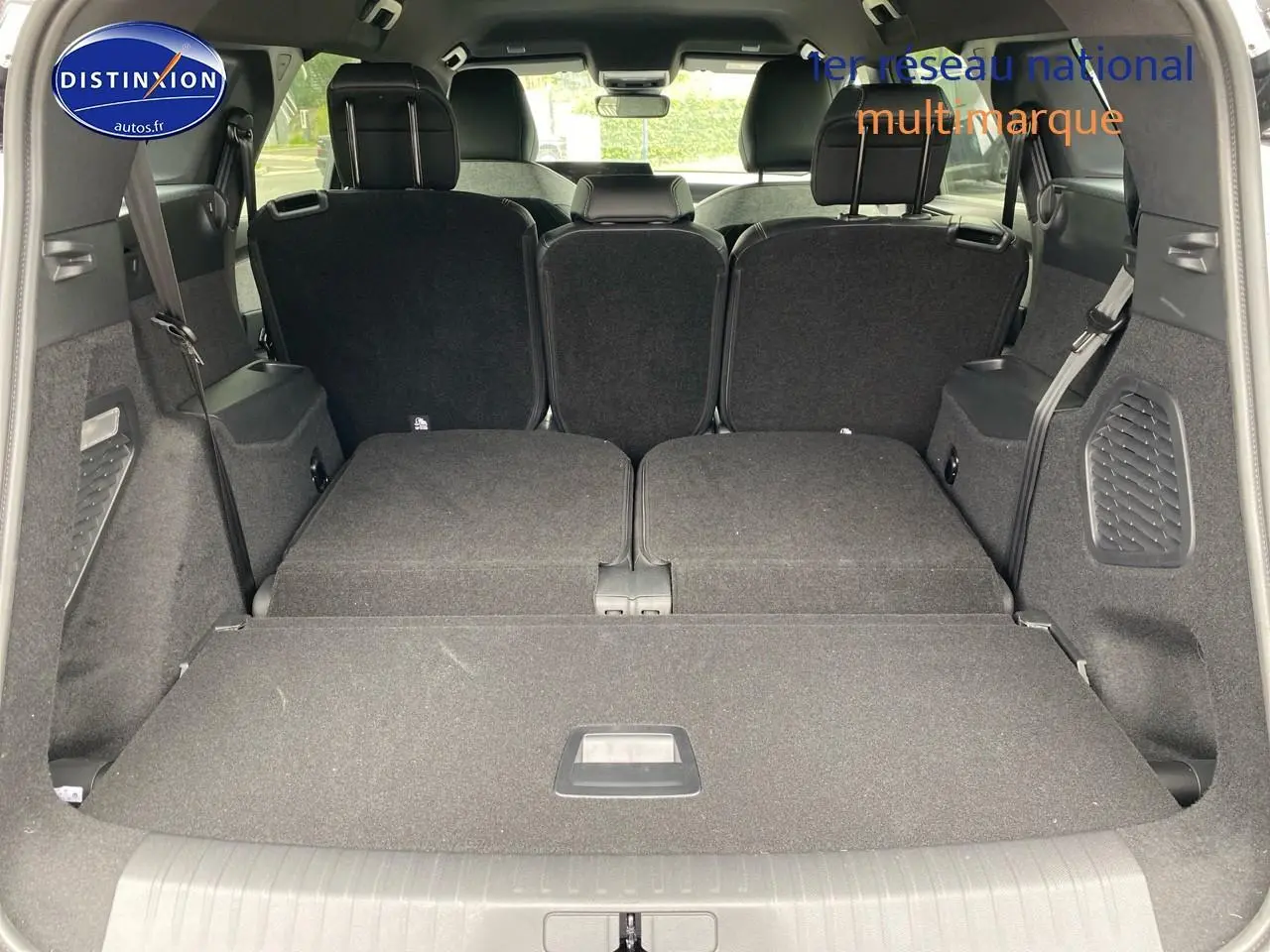 Vue arrière du coffre du Peugeot 5008 gris titane avec banquette arrière partiellement rabattue et sièges rang 3 relevés.
