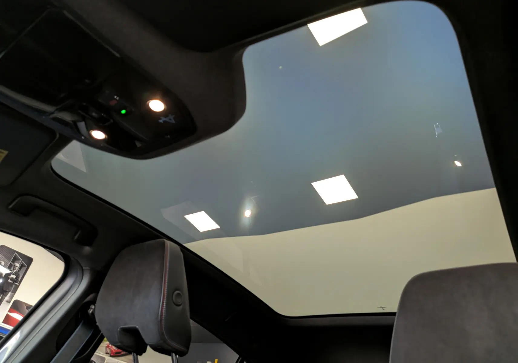 Vue intérieure du toit panoramique avec éclairage LED et appuie-tête en cuir noir du Renault Rafale gris schiste.