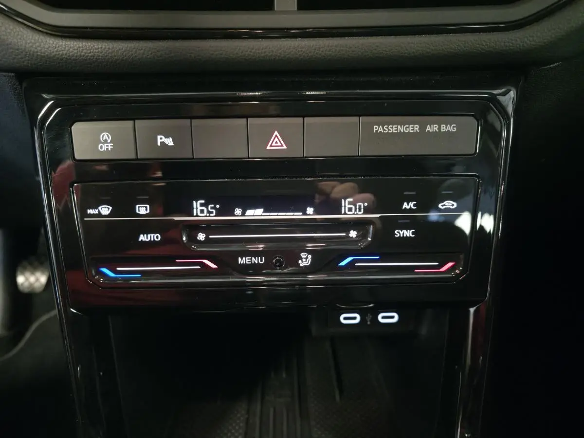 Vue rapprochée du tableau de bord du Volkswagen T-Cross gris, affichant la climatisation automatique bi-zone et ports USB-C.
