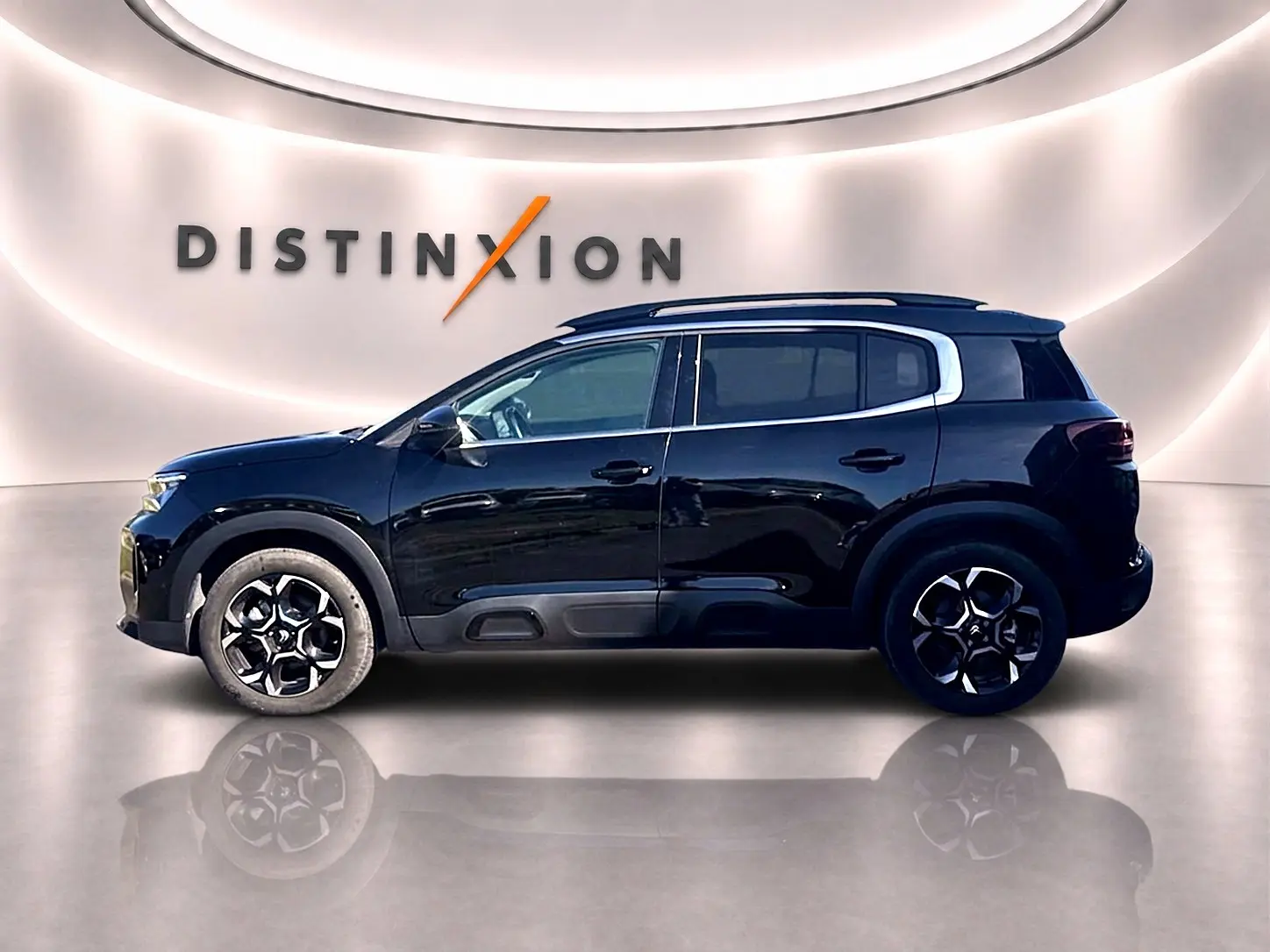 Profil droit d'un Citroën C5 Aircross noir 2025 avec barres de toit et jantes alliage distinctives, en studio lumineux.