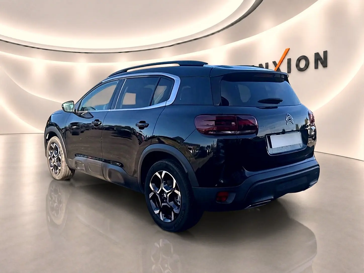 Vue 3/4 arrière droite d'un Citroën C5 Aircross noir avec jantes alu et barres de toit visibles en intérieur.