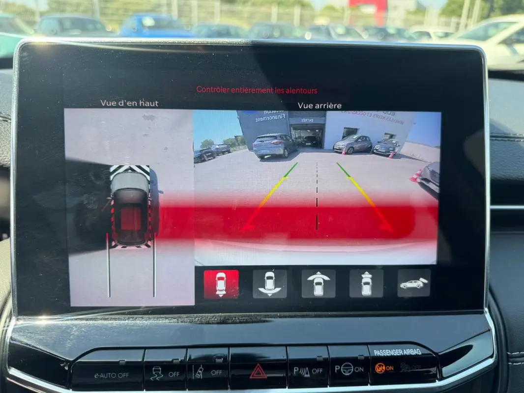 Écran tactile intérieur montrant la caméra de recul et vue en hauteur du Jeep Compass blanc 2025 en stationnement.