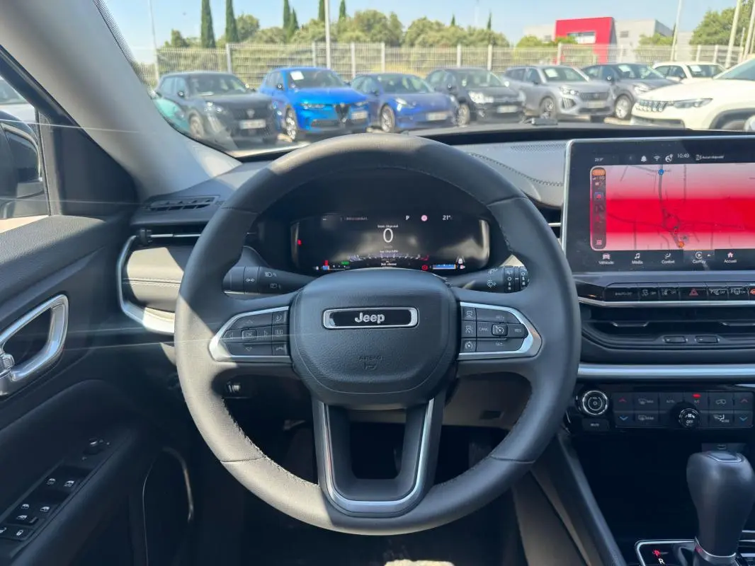 Vue intérieure centrée sur le volant Jeep d'un Compass 2025 avec tableau de bord numérique et écran tactile large.