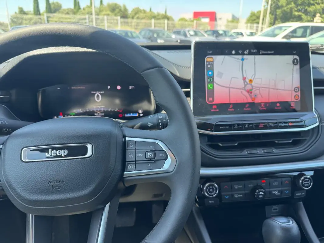 Vue intérieure centrée sur le volant Jeep noir et l'écran tactile affichant un GPS dans un Compass blanc 2025.