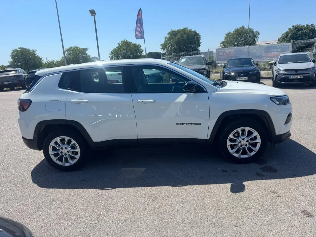 Vue latérale droite d'un Jeep Compass blanc 2025, avec jantes alliage et logo "Compass" visible sur la porte.
