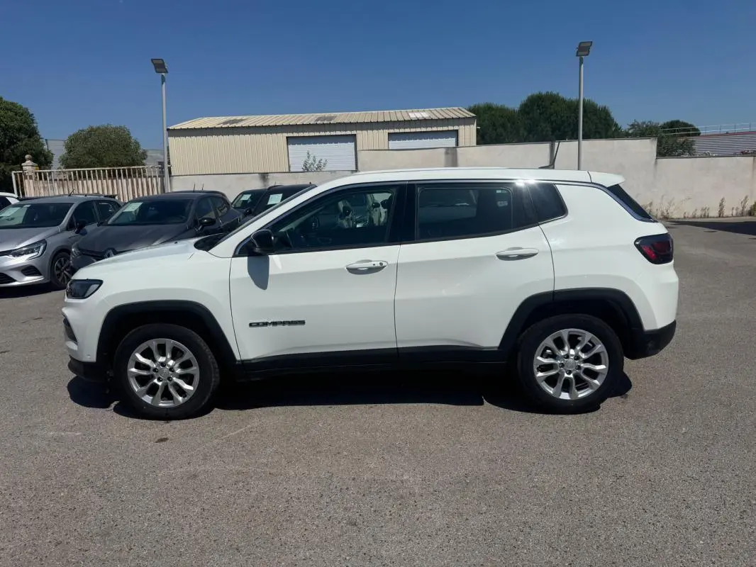 Jeep Compass blanc vu de profil côté gauche, avec jantes alliage et détails noirs contrastants.