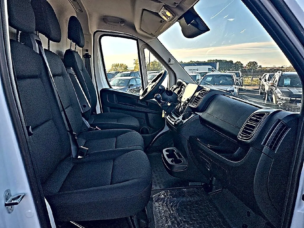 Vue intérieure côté conducteur du Peugeot Boxer Fourgon blanc, montrant la banquette 2 places et le tableau de bord moderne.