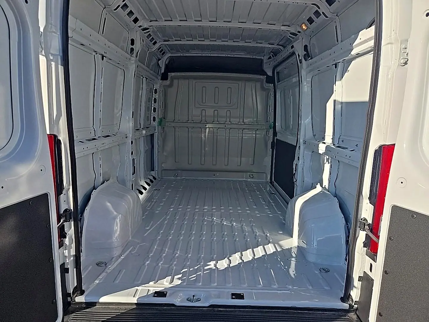 Vue intérieure arrière du fourgon Peugeot Boxer blanc, montrant l'espace de chargement vide et la cloison pleine.