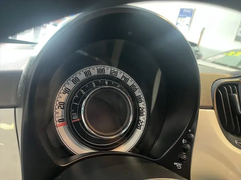 Gros plan sur le compteur circulaire noir et blanc du tableau de bord de la Fiat 500 blanche, version hybride 2021.