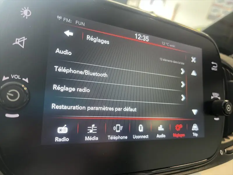Écran tactile central de la Fiat 500 blanche de 2021 affichant le menu Réglages avec options audio et Bluetooth.