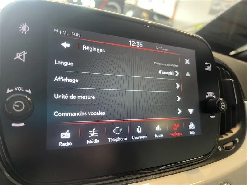 Écran tactile central affichant le menu Réglages dans l'habitacle d'une Fiat 500 blanche de 2021.