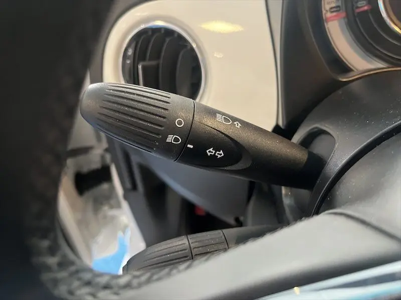Gros plan sur la manette de clignotants noire dans l'habitacle blanc d'une Fiat 500 blanche de 2021.