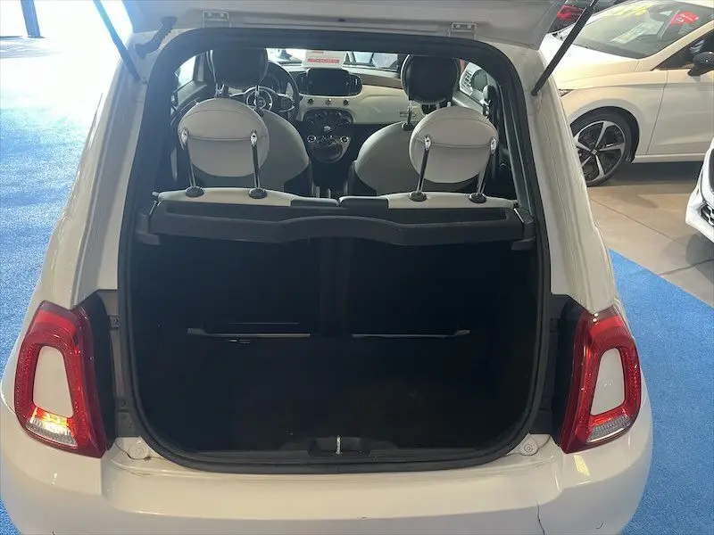 Vue arrière ouverte d'une FIAT 500 blanche montrant le coffre vide et l'intérieur clair avec sièges avant visibles.