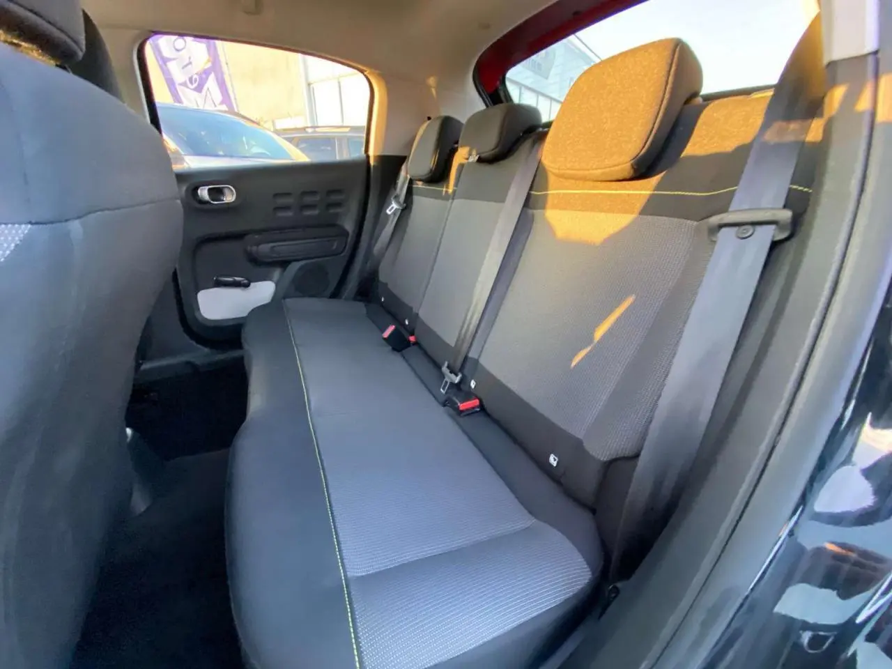 Banquette arrière vue côté gauche de la Citroën C3 Shine 2023 noire toit rouge avec ceintures et appuie-têtes intégrés.