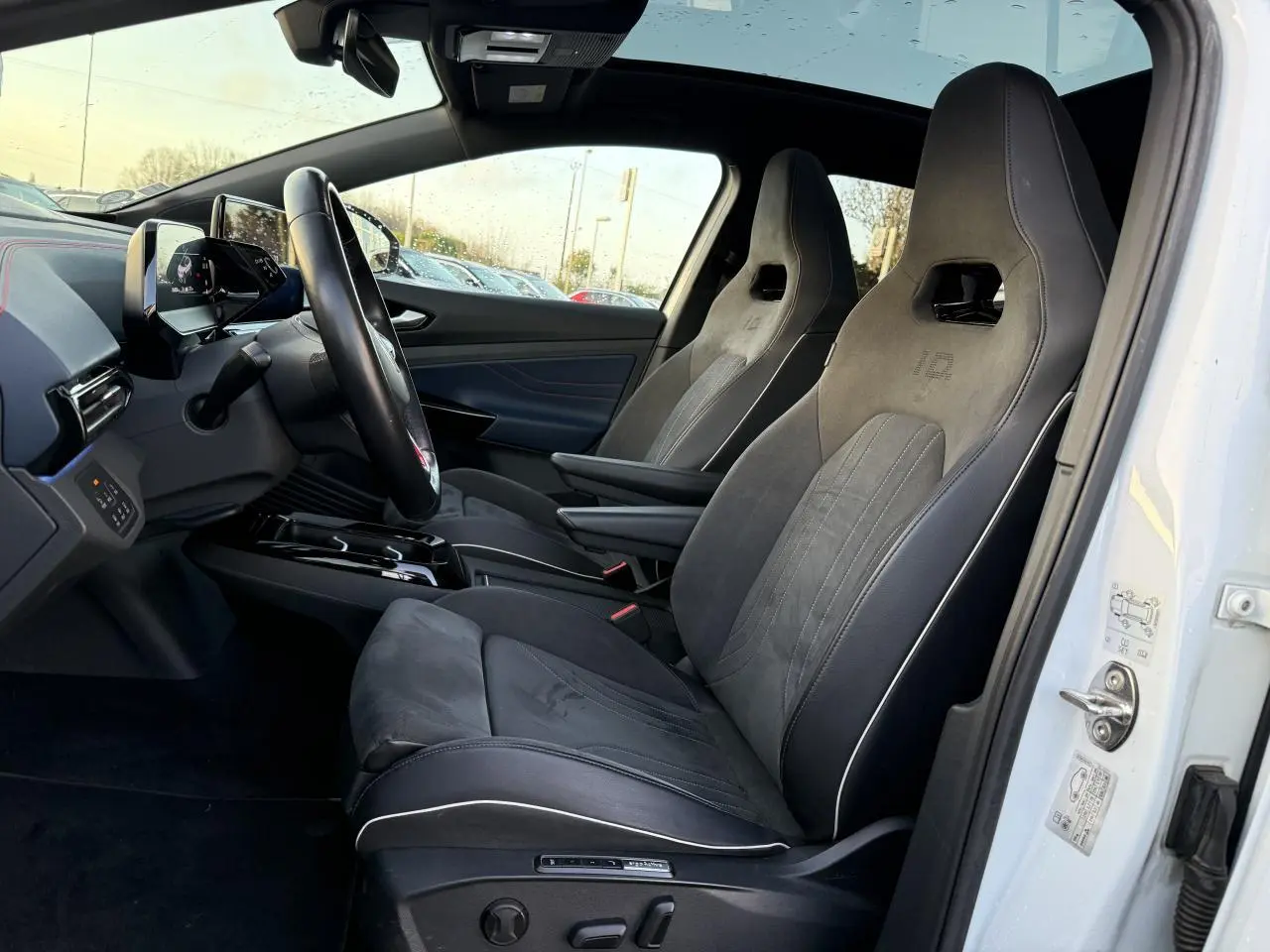 Intérieur côté conducteur d'un Volkswagen ID.4 GTX blanc, sièges sport en ArtVelours bi-colore avec toit panoramique en verre.