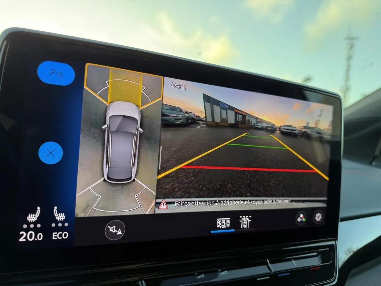 Écran intérieur du Volkswagen ID.4 GTX blanc montrant la caméra 360° et l'affichage de la vue avant en stationnement.