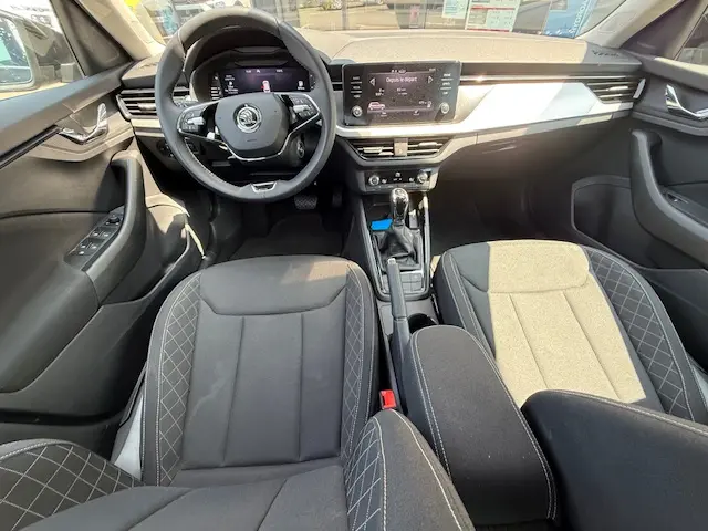 Vue intérieure avant du Skoda Kamiq 2024 noir, montrant le volant cuir multifonctions et l'écran tactile central.