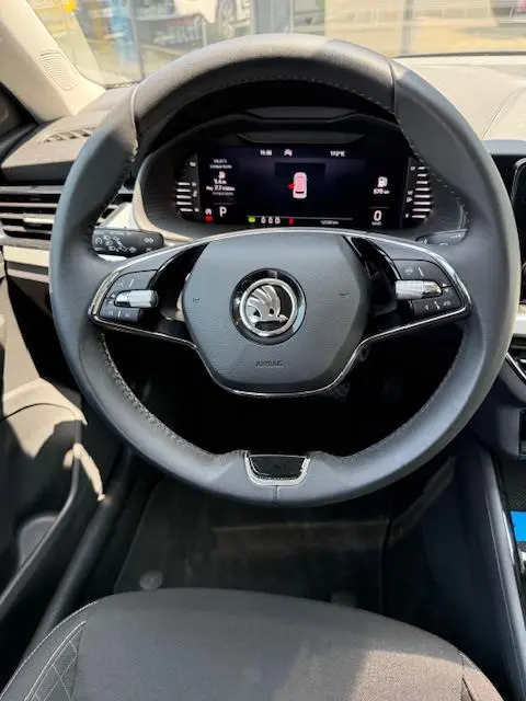 Vue intérieure centrée sur le volant cuir noir et le tableau de bord numérique du Skoda Kamiq 2024.