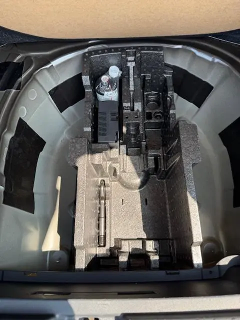 Vue plongeante sur le rangement sous tablette du coffre du Skoda Kamiq noir 2024, espace pour roue galette et outils.