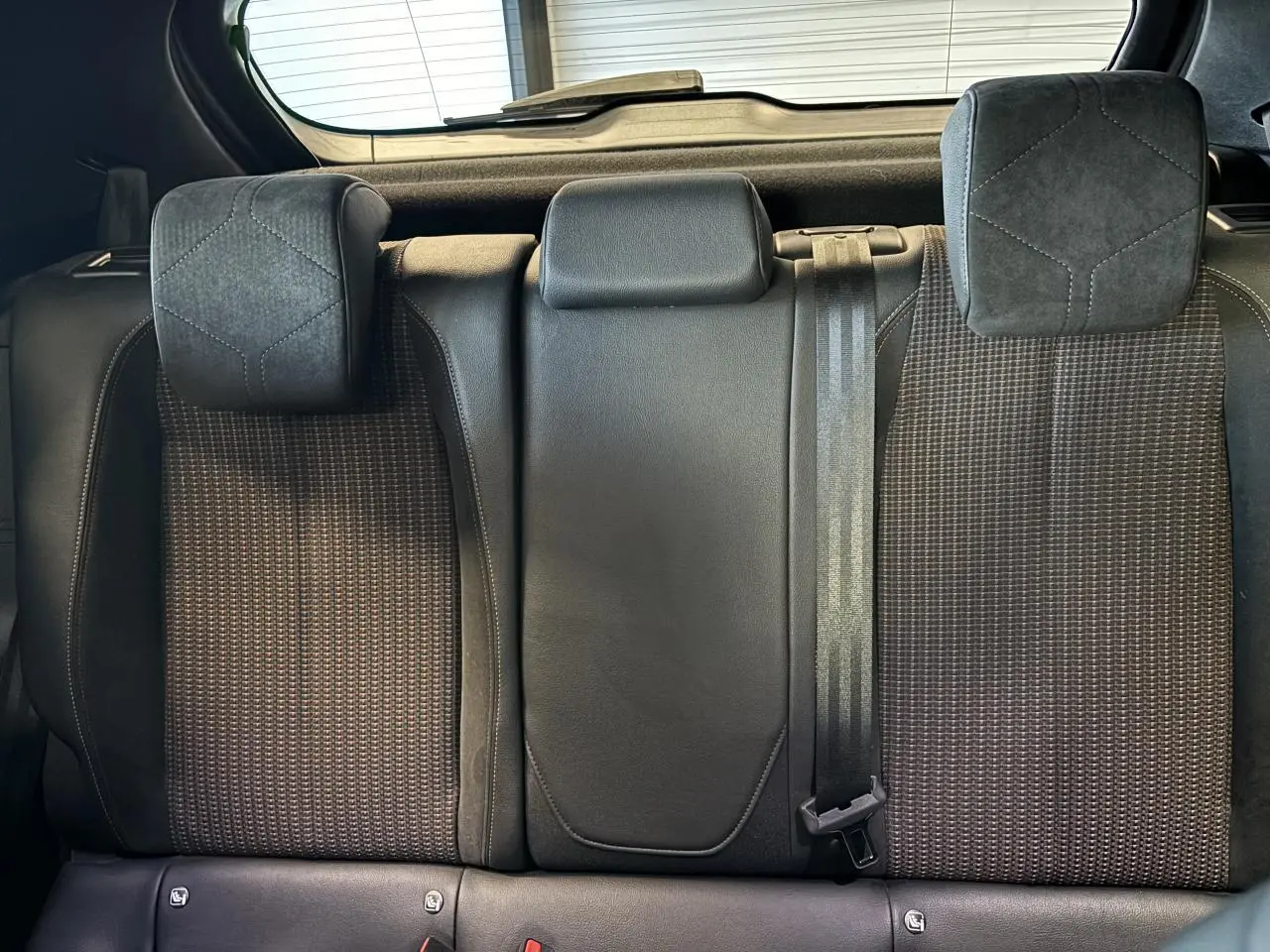 Vue rapprochée des sièges arrière en tissu et cuir noir du DS3 Crossback 2024, avec appuie-têtes et ceinture de sécurité.