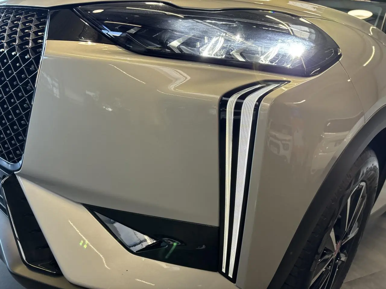 Gros plan sur l'avant droit du DS3 Crossback 2024 en Crystal Pearl, mettant en valeur ses feux LED verticaux et la calandre distinctive.