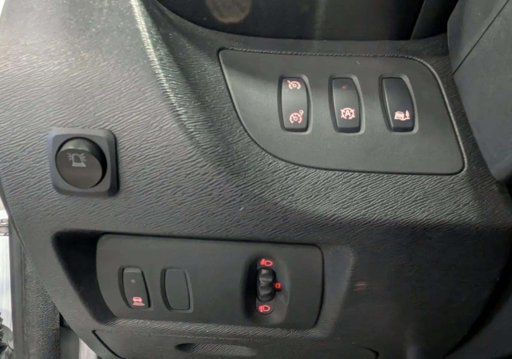 Gros plan sur les commandes intérieures noires du tableau de bord côté gauche du Renault Kangoo Express blanc.