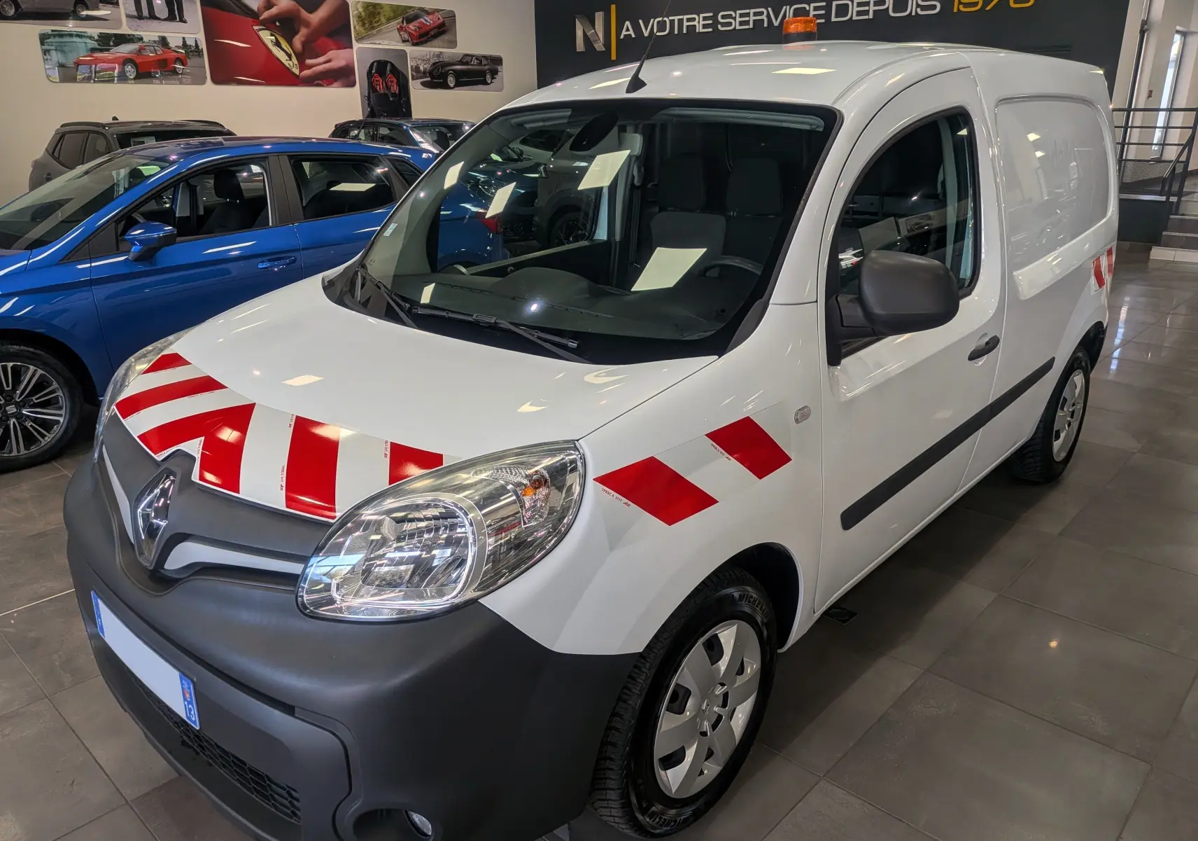 Renault Kangoo Express blanc minéral en 3/4 avant droit avec bandes rouges de signalisation sur capot et aile.