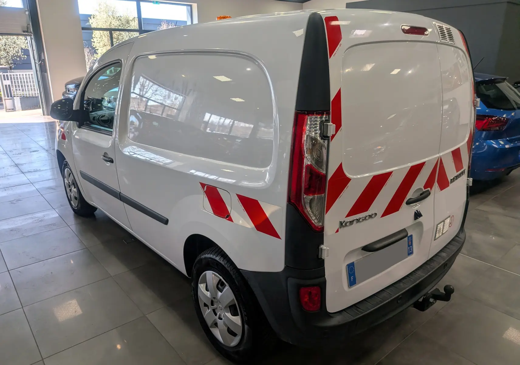 Vue 3/4 arrière droite du Renault Kangoo Express blanc minéral avec bandes rouges réfléchissantes sur les portes arrière.