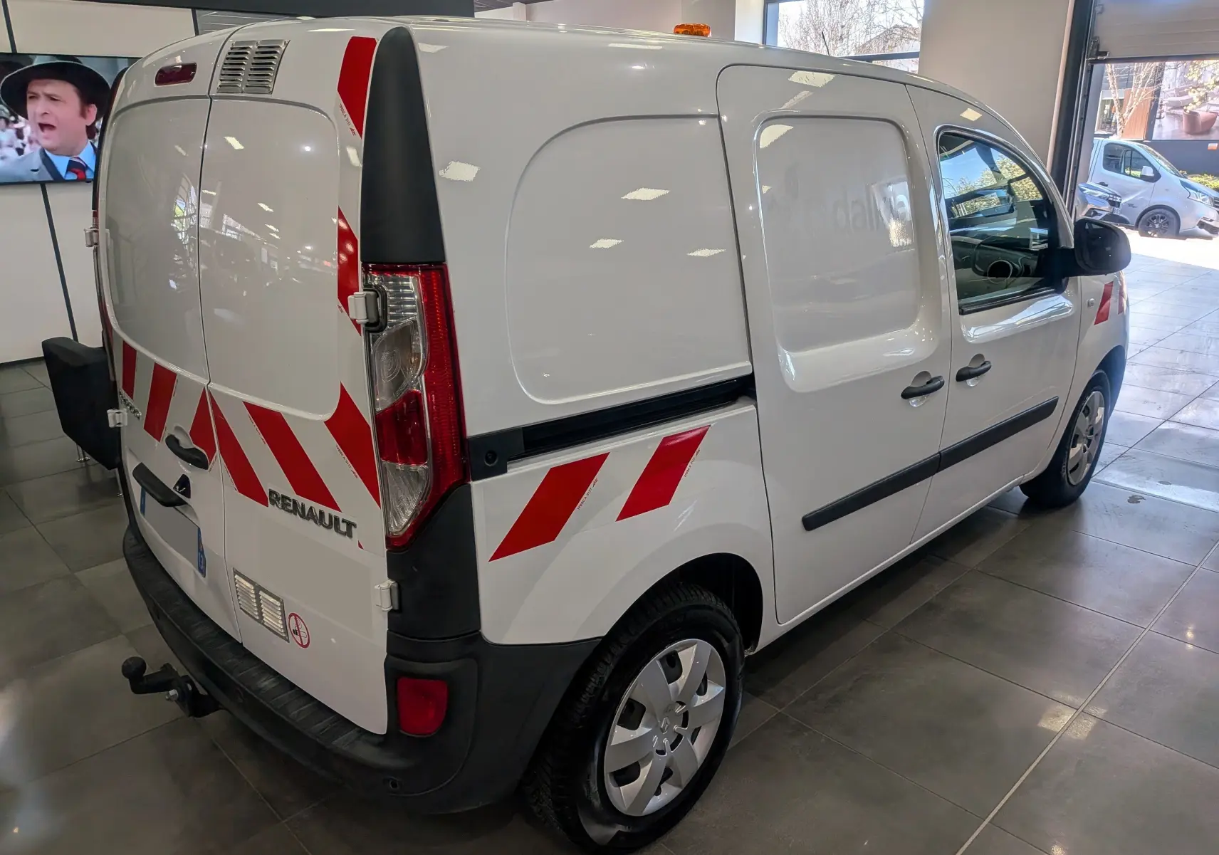 Renault Kangoo Express blanc minéral vu en 3/4 arrière droit avec bandes rouges réfléchissantes et attelage.