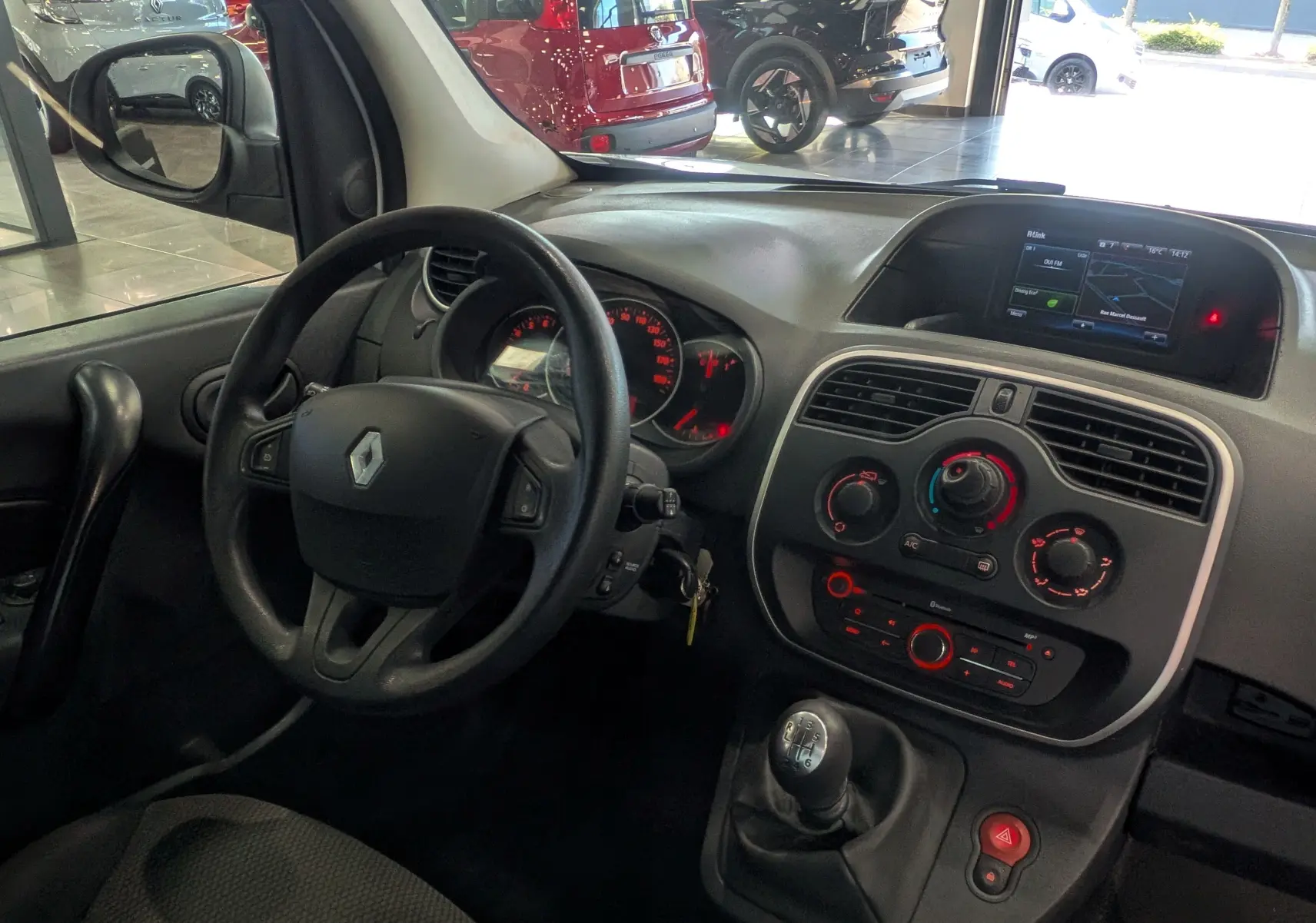 Vue intérieure côté conducteur du Renault Kangoo Express blanc, montrant le volant, tableau de bord et écran R-Link.