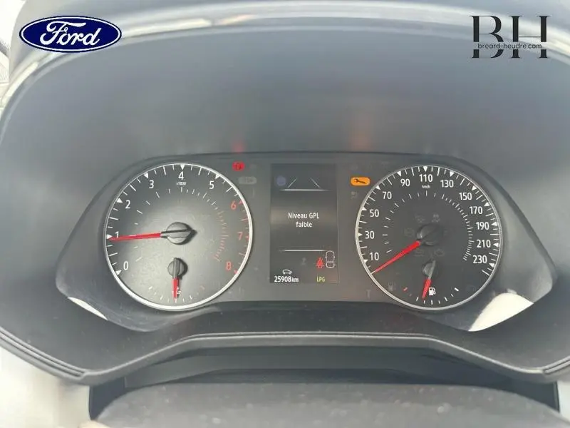 Vue rapprochée du tableau de bord d'une Renault Clio blanc, affichant un message d'alerte niveau GPL faible.