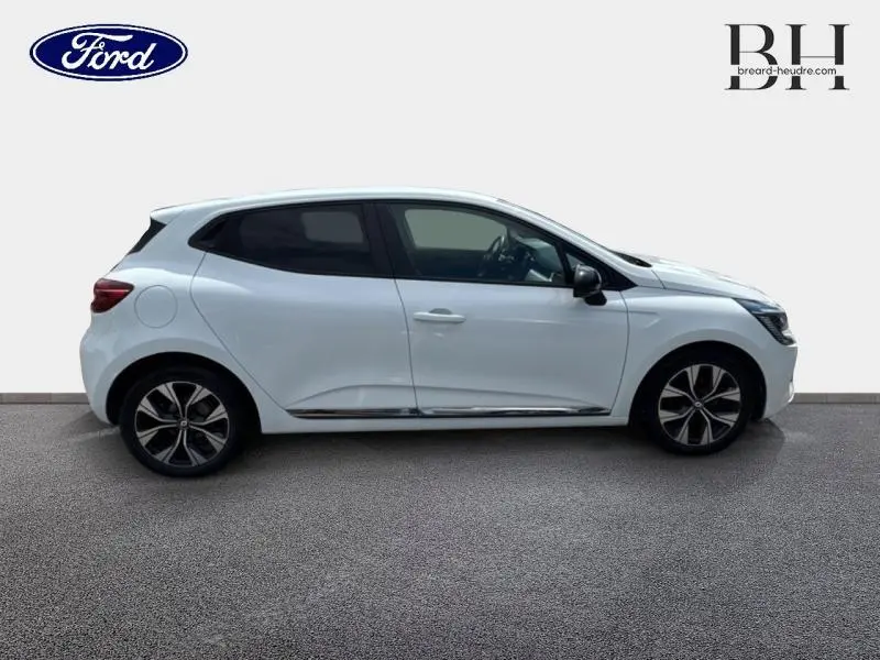 Profil droit d'une Renault Clio blanche 2023 avec vitres arrière surteintées et jantes alliage noires.