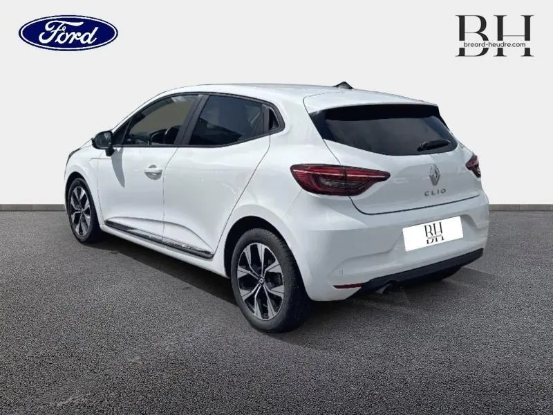 Renault Clio blanc glacier vue 3/4 arrière droit, vitres arrière surteintées et jantes alliage distinctives.