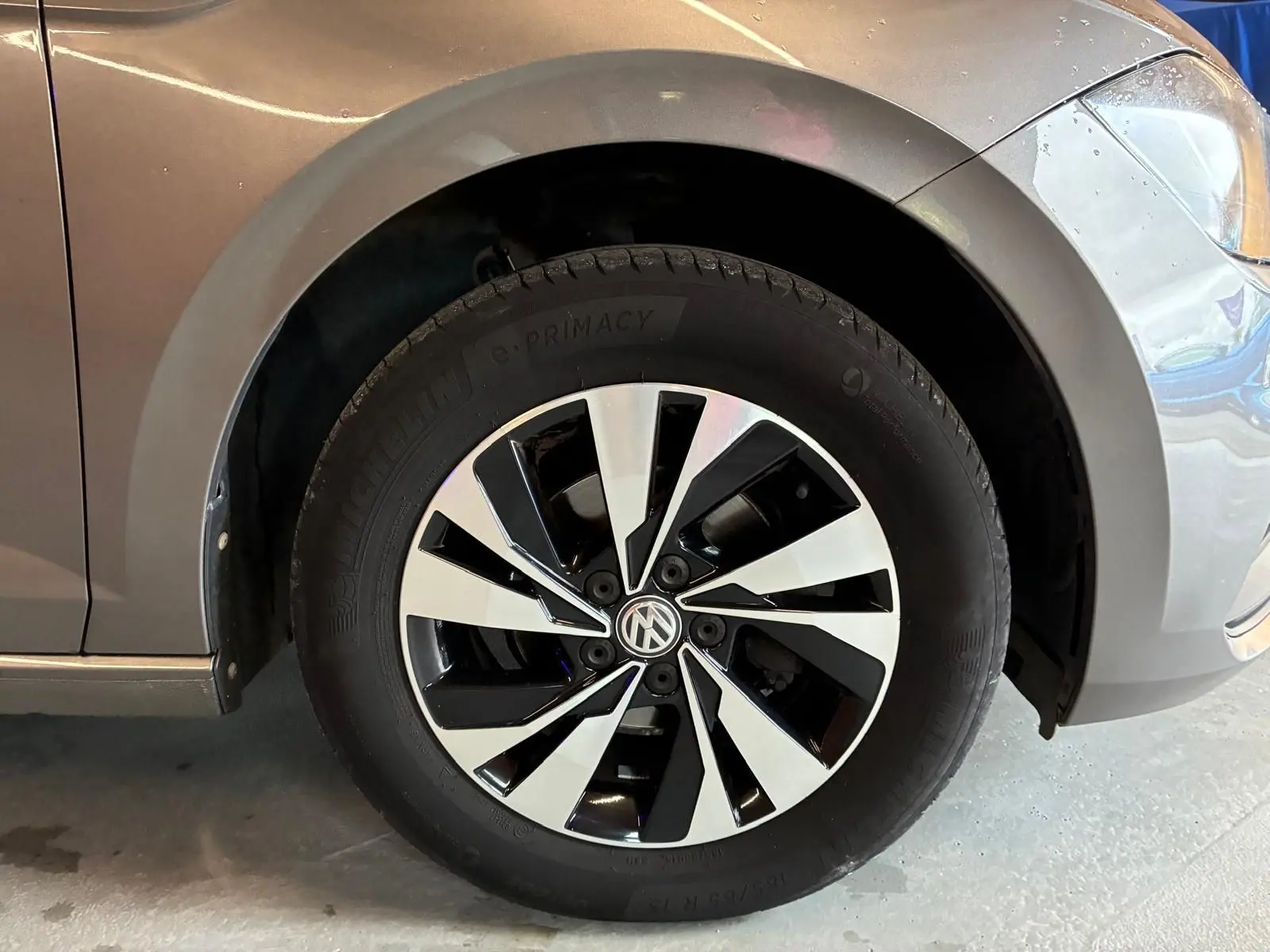 Gros plan sur la roue avant gauche d'une Volkswagen Polo gris métallisé avec jante alliage bicolore moderne.